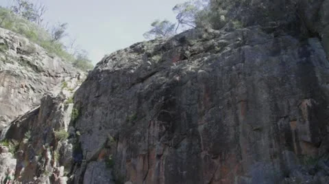Pan left of rock formation &amp; fauna above raging Nethercote Falls, NSW, Australia 動画素材 11234908