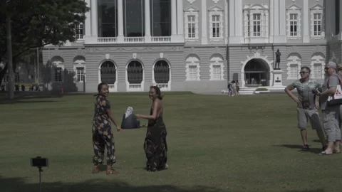 Pan left slow mo day 2 girls jump in front mobile phone victoria theater Stock Footage 230566931