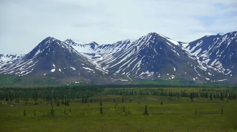 Pan Left Snow Capped Mountain Range with Green Field Stock Footage 37399178