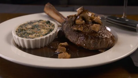 Pan left of tomahawk steak with sides  Stock Footage 112575992