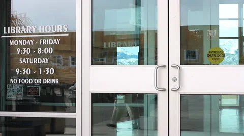 PAN ON LIBRARY HOURS ON THE DOOR OF THE LIBRARY Stock Footage 35730898