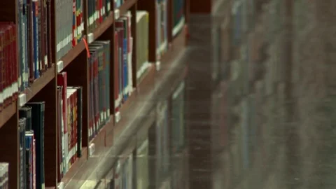 Pan up of library shelves in perspective; interesting light and focus Stock Footage 77338934