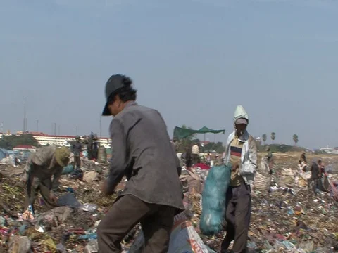 Pan of many people picking through garbage on top of garbage dump Stock Footage 90271105