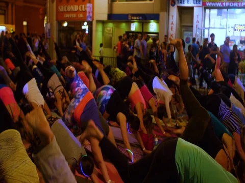 Pan of mass group doing yoga Ottawa 2017 Glowfair. Stock Footage 76798067