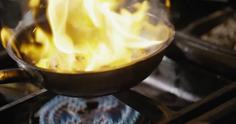 Pan with meat cooking with flames over stove Stock Footage 274652548