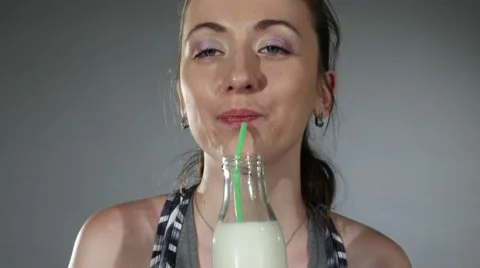 Pan up of a milk bottle being drunk by a pretty woman in her fitness gear Stock Footage 62472539