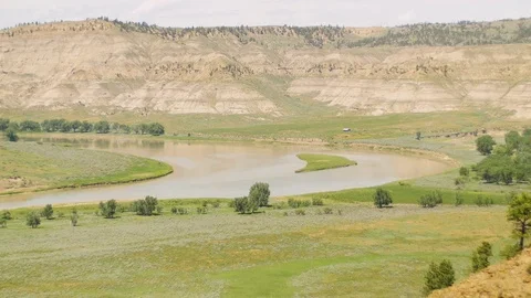 Pan of muddy river to old cabin on bank Stock Footage 83692250