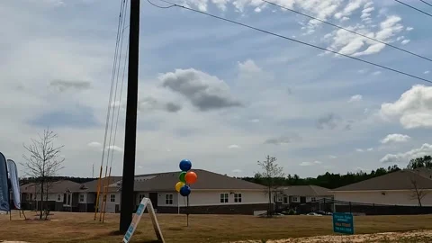 Pan of new  Apartment complex buildings balloons street pan Stock Footage 179956745