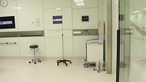 Pan of nurse entering and using touch screen monitor in operating theatre. 스톡 동영상 129895005