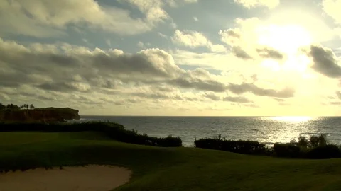 Pan from ocean waves to golf course putting green with island mountains Stock Footage 125332936