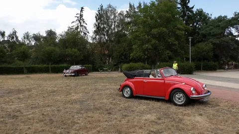 Pan: Old Beetle convertible and historic Jaguar MK2 arriving at oldtimer meeting Stock Footage 114438190