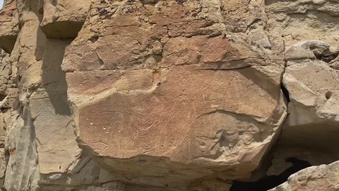 Pan to old petroglyphs at Writing-on-Stone Aisinai’pi sandstone cliff 스톡 동영상 338996769