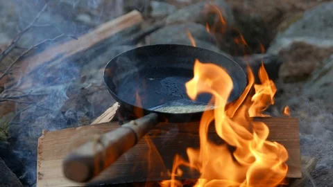Pan over campfire cooking meat Видео 124305876