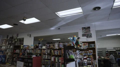 Pan over comic book store people reading boxes slow motion 4K Stock Footage 171973969