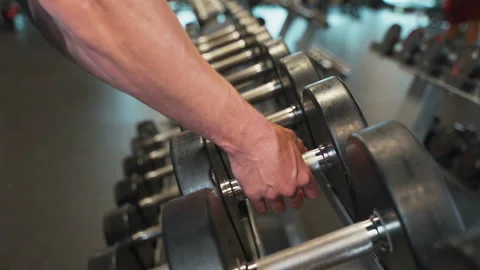 Pan Over Dumbbells As Man Grabs One at Gym | Slow Motion Stock Footage 167284743