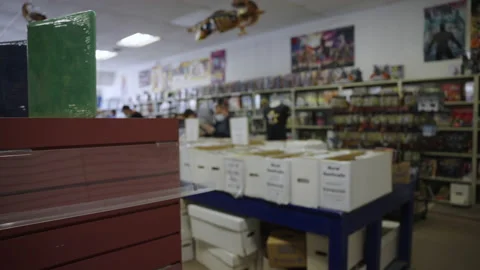 Pan over empty comic book store people reading boxes slow motion 4K Stock Footage 171974148