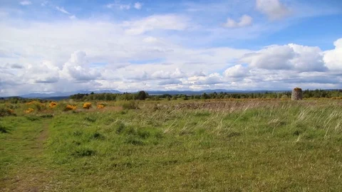Pan over grassy field with stone structure and red flag Stock Footage 89588281