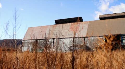 Pan Over a Remote, Rundown Storage Building in a Field of Tall Grass Video stock 22243517