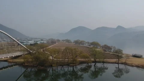 Pan over river in Winter, reflection of trees and bridge in the water aeria view Stock Footage 245834376