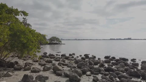 Pan, pan view, View over rocks towards blue bay water with blue and white clouds Stock Footage 260644650