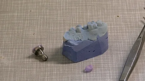 Pan: Part of a teeth model, a crown, tweezers and dentistry gear in a dental lab Video stock 76779433