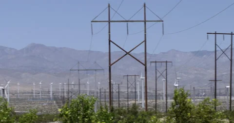 Pan from power lines to turbines generating power at wind farm 4K Stock Footage 63846179