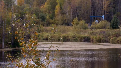 Pan onto pump jack working in a field for oil and gas industry. Video stock 59840462