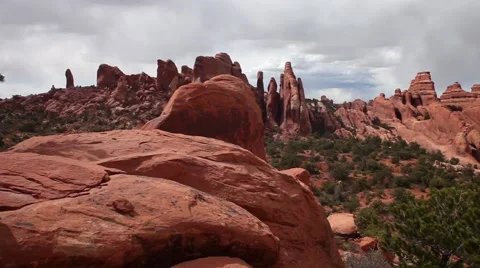 Pan red rock formations, Arches National Park, gray sky, clouds, green tree Stock Footage 41751191