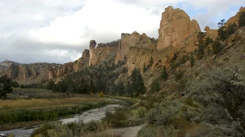 Pan up to reveal cliff landscape while hiker walks at Smith Rock State Park Stock Footage 132659473