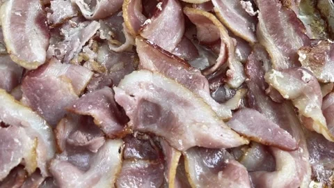 Pan from right across cooked bacon rashers on aluminum foil, viewed from above. 스톡 동영상 334642250