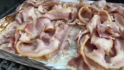 Pan from right across cooked bacon rashers on aluminum foil, viewed from above. 스톡 동영상 334642313