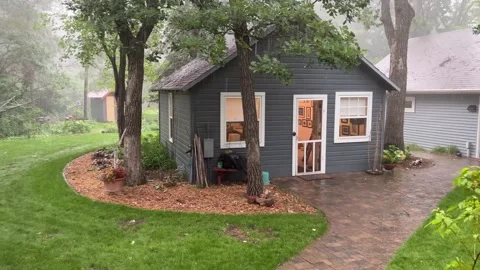Pan right across cottage scene in a heavy downpour Stock Footage 273176453