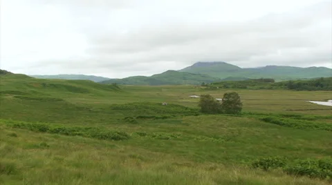 Pan right on flat grassland with small river, Highland mountains Stock Footage 39815418