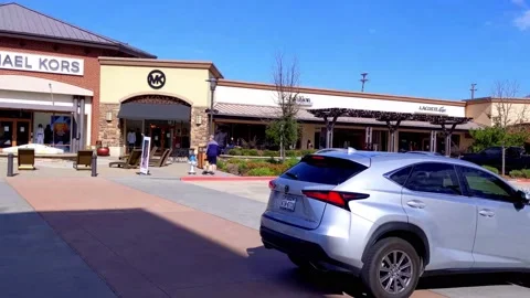 Pan right to left of a few premium outlet stores on a sunny day at outdoor mall Vídeos de archivo 165527370