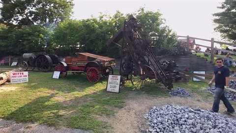 Pan Right of Man Demonstrating Antique, Rock-Crushing Loader Machine Stock Footage 79794053
