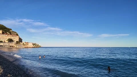 Pan right of a pebble beach and blue sea at sunset 스톡 동영상 336922836