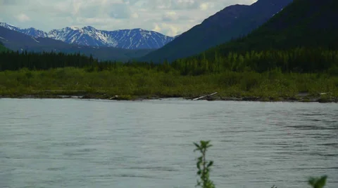 Pan Right, River Flows Through Green Valley in Mountain Shadow Stock Footage 37436756