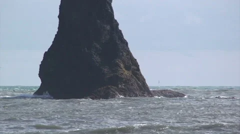 Pan right on sea stack pinnacle with waves crashing Stock Footage 37584061
