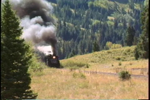 Pan-right shot of a steam freight train chug through the Colorado mountains. Stock-Footage 340831