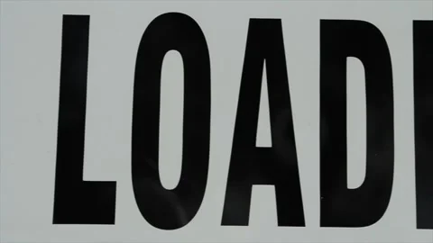 Pan right on sign caption that says bus loading zone, large in frame, black Stock Footage 246135933
