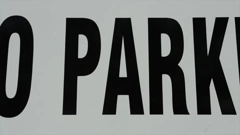 Pan right on sign caption that says no parking, large in frame, black writing Vídeo Stock 246135944