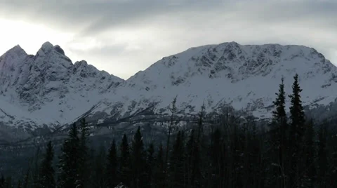 Pan Right Snow Covered Mountain Range with Trees in Foreground Stock Footage 38058681