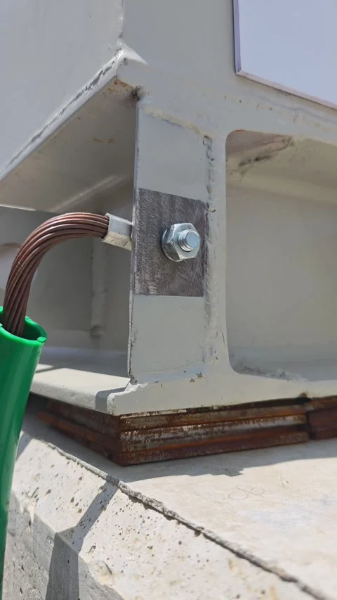 Pan right video of a bare copper grounding wire bolted to a white metal. Stock Footage 338298492