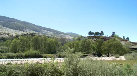 Pan on river that flows to right behind rocks along valley in bloom Video stock 49556103