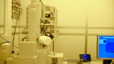 A pan of a scientist working on a big electrone microscope in the clean Vidéo 94569957