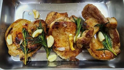 Pan-Seared Pork Chops with Garlic and Fresh Rosemary Sprigs in a Stainless .. Stock-Fotos