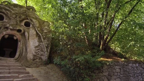 Pan to see sculpture of Orcus, Park of Monsters, Sacred Wood, Bomarzo, Italy Stock Footage 83922704