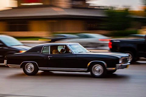 Pan shot of a black Chevrolet Malibu frozen in motion on cruise night at sunset Stock Photos