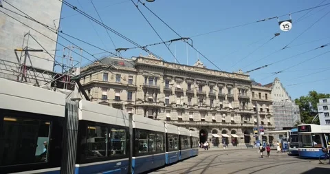 Pan shot of blue trams turning at Paradeplatz in front of UBS bank in Zurich Stock Footage 341854075