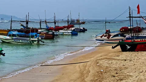 Pan shot of boats on the beach during the day in Weligama Beach Stock Footage 302352145
